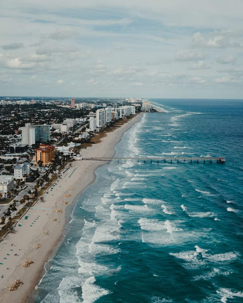 A stunning aerial view of a beachfront Jacksonville Florida cityscape with a long pier and turquoise waves.