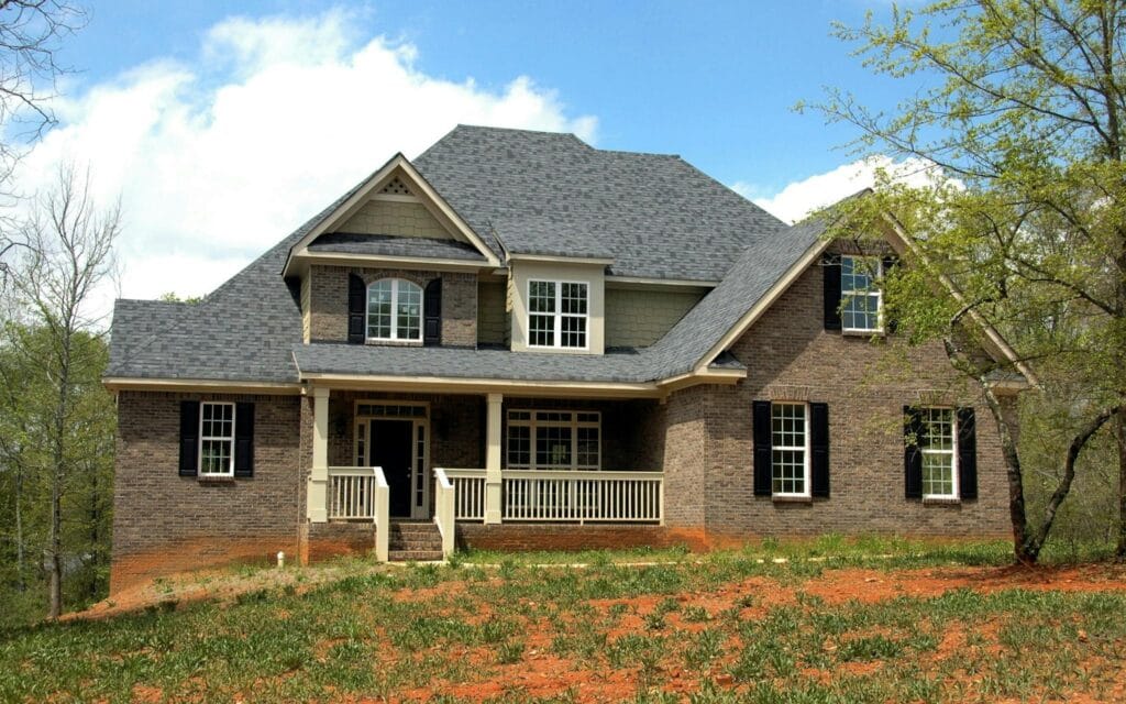 Classic two-story brick house with gable roof and front lawn in suburban setting. One of many New Homes For Sale in Missouri