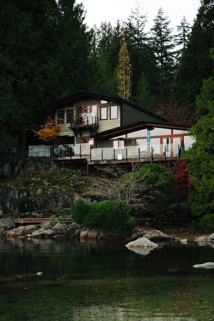 Modern house nestled in a lush forest by the water.