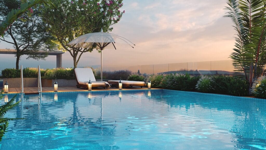 Swimming pool with lounge chairs and ocean view at sunset.