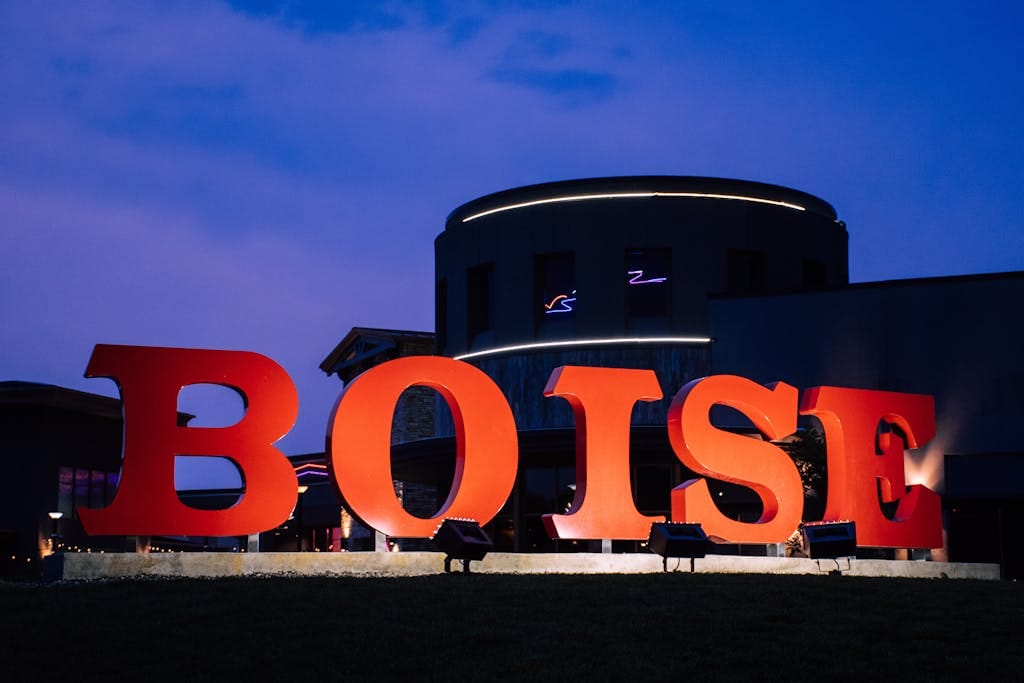 Large red 'Boise' sign against a modern building at twilight.