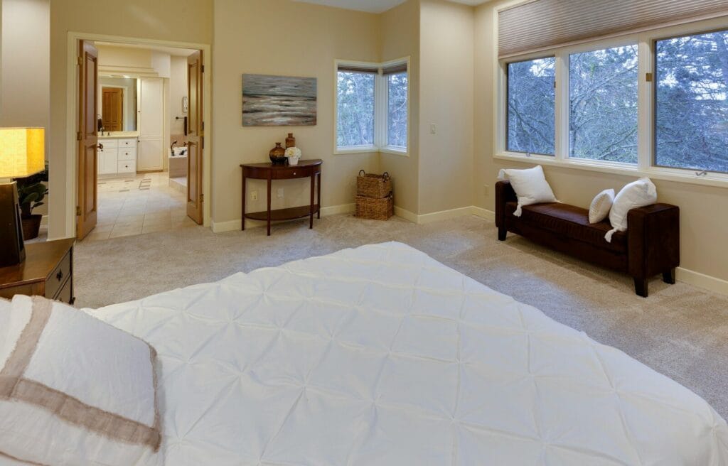 Bedroom with furniture including a bed near open bathroom door