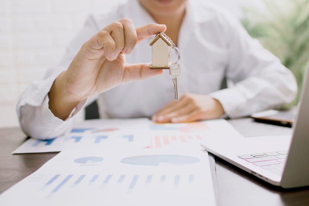 Insights Real estate professional presenting a house model with keys, symbolizing property investment and ownership.