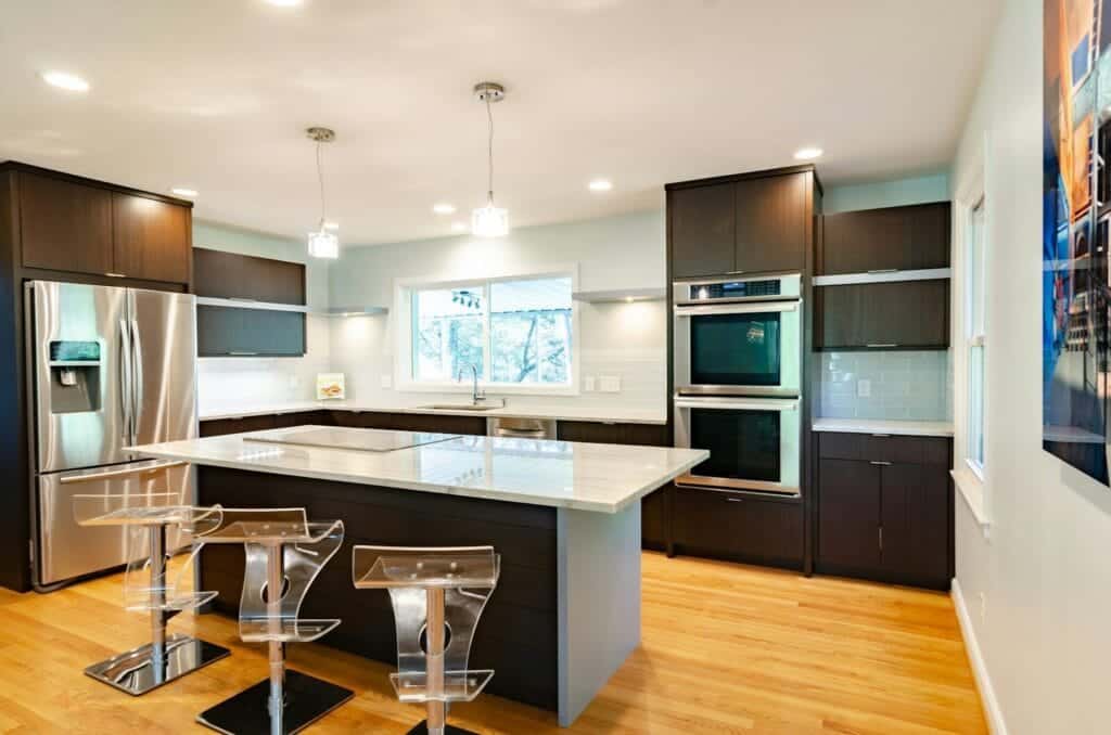 Kitchen with stainless steel appliances and island with three clear glass bar stools